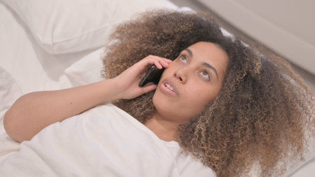 African American Woman Talking on Phone in Bedの写真素材