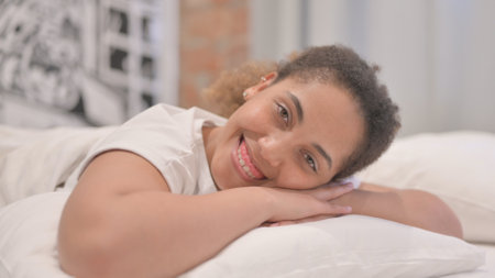 Smiling African American Woman Looking at Camera Lying on Stomach