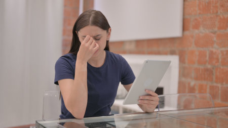 Young Latina Woman Upset by Loss on Tabletの写真素材