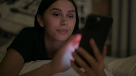 Close Up of Young Latina Woman using Smartphone at Night in Bed