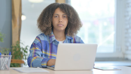 Young African Woman Looking at Camera while Working on Laptopの写真素材