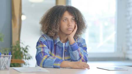 Pensive Young African Woman Thinking while Sitting at Homeの写真素材