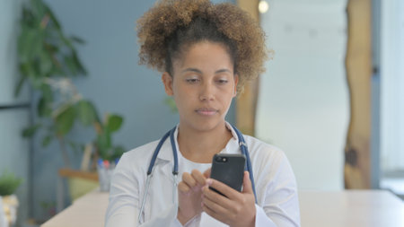 Female African Doctor Using Smartphone in Clinicの写真素材