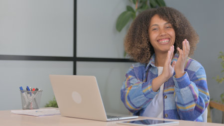 African American Woman Clapping at Camera while Working in Office