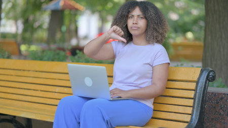 Thumbs Down by Young African Woman Working on Laptop Outdoor