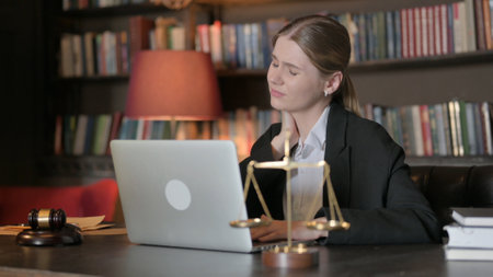 Female Lawyer with Neck Pain Working on Laptopの写真素材