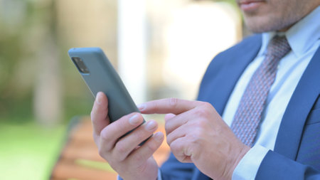 Close Up of Businessman Using Phone while Sitting Outdoorの写真素材