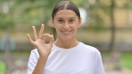 Hispanic Woman Doing Ok Sign while Standing Outdoorの写真素材
