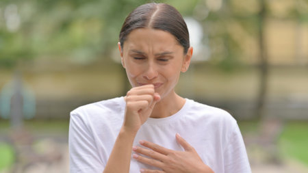 Sick Hispanic Woman Coughing while Standing Outdoorの写真素材