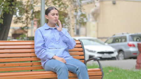 Latin Woman with Toothache Sitting Outdoor