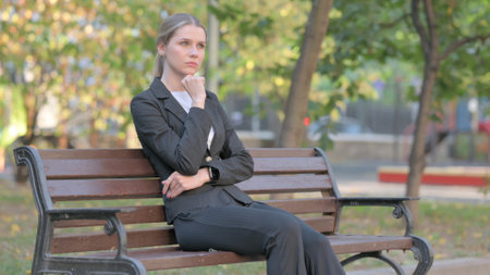 Pensive Businesswoman Sitting Outdoor on Benchの写真素材