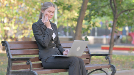 Businesswoman with Toothache Working on Laptop Outdoorの写真素材
