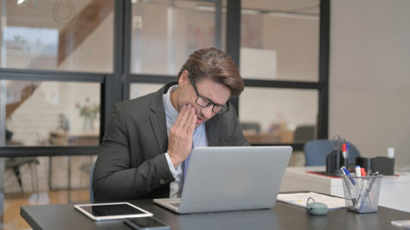 Businessman with Toothache Working on Laptop in Office