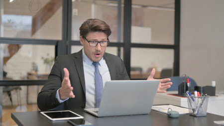Businessman Shocked by Loss on Laptop in Officeの写真素材