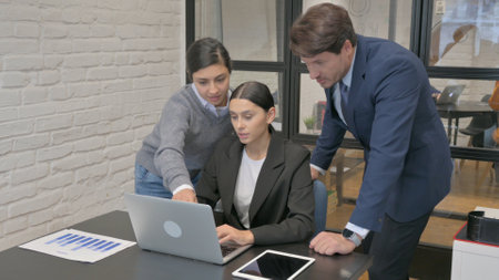 Hispanic Businesswoman Working with Teammate on Laptopの写真素材