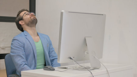 Young Man Shocked by Loss on Desktop Computer in Office