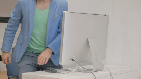 Young Man Leaving Office after Working on Desktop