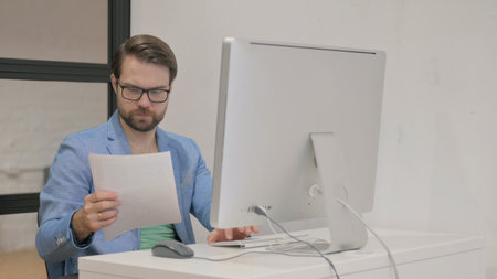 Young Man with Business Report Working on Desktop
