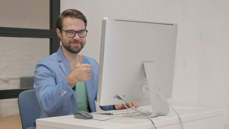 Thumbs Up by Young Man Using Desktop Computer