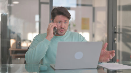 Angry Man Talking on Phone at Work