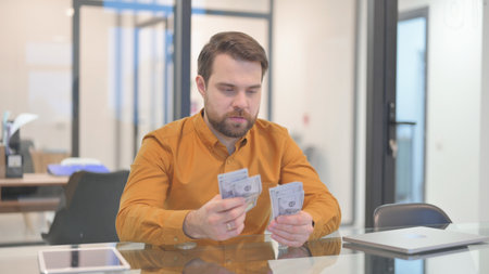 Middle Aged Businessman Counting Money in Office
