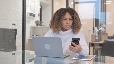 African Woman Working on Laptop and Using Smartphone