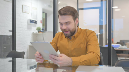 Casual Creative Man Celebrating Success on Tabletの写真素材