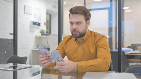 Casual Creative Man Counting Money in Officeの写真素材