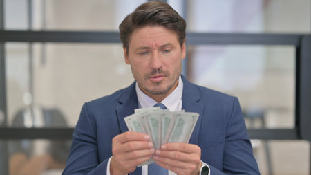 Portrait of Middle Aged Businessman Counting Money at Work