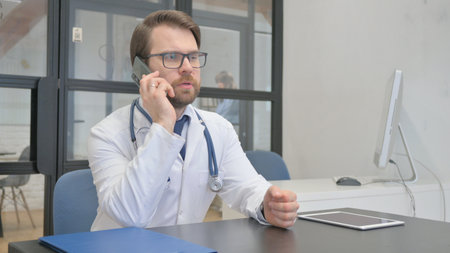 Mature Adult Doctor Talking on Phone with Patient in Hospitalの写真素材