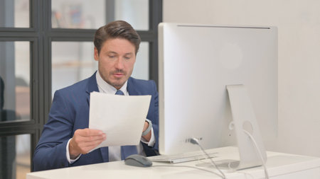 Middle Aged Businessman Working on Documents and Desktop