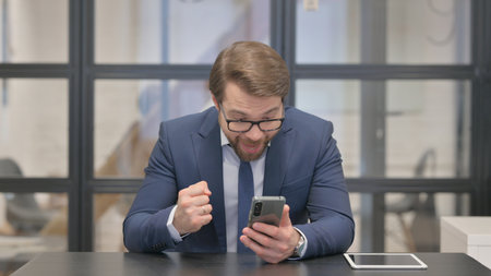 Young Businessman Celebrating Success on Phoneの写真素材