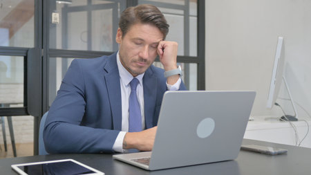 Mature Adult Businessman Resting on Office Deskの写真素材