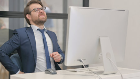 Young Businessman with Spinal Pain Working on Computerの写真素材
