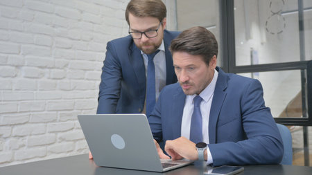 Standing Businessman Helping Partner at Work, Using Laptopの写真素材