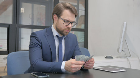 Earning Businessman Counting Money at Workの写真素材