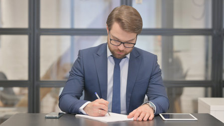 Young Businessman Writing a Letter in Officeの写真素材