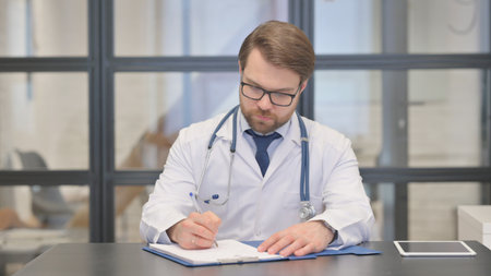 Doctor Writing a Treatment and Medical Report in Hospitalの写真素材