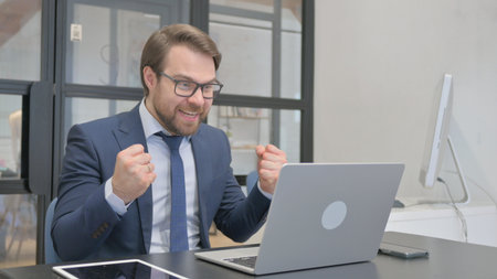 Young Businessman Cheering Success on Laptopの写真素材
