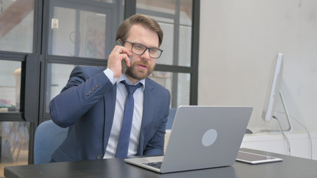 Young Businessman Talking on Phone at Workの写真素材