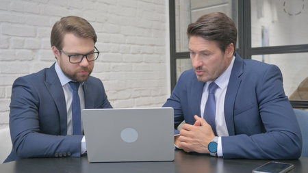 Businessmen Working on Laptop in Office Togetherの写真素材