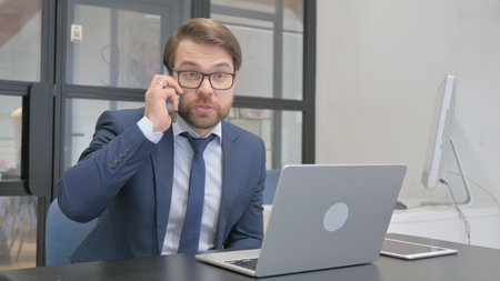Angry Young Businessman Talking on Phoneの写真素材
