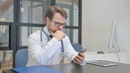 Mature Adult Doctor Working on Smartphone in Hospitalの写真素材
