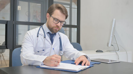 Mature Adult Doctor Writing Medical Report in Hospitalの写真素材
