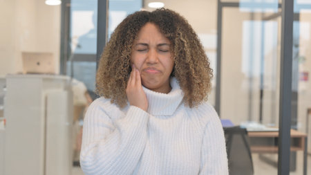 Uncomfortable African Woman with Toothache in Officeの写真素材