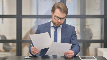 Young Businessman Reading Documents at Workの写真素材