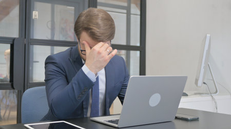 Young Businessman having Migraine while at Workの写真素材