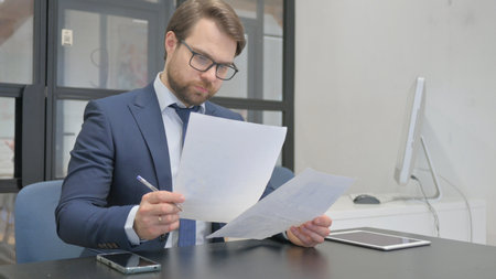 Businessman Reading Business Report at Workの写真素材