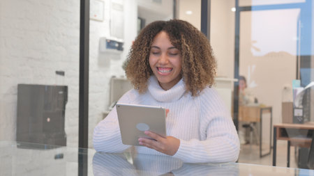 African Woman Doing Video Chat on Tablet in Officeの写真素材
