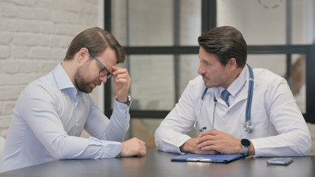 Man with Headache Consulting Middle Aged Doctorの写真素材